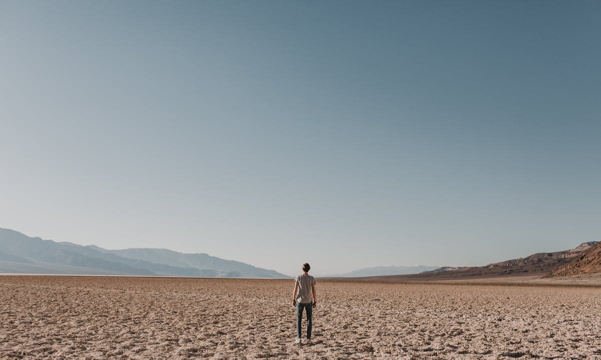 Siccità in Italia: un uomo cammina su un terreno desertificato dalla siccità