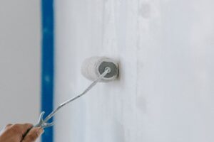 Mano che pittura un muro con un rullo.
