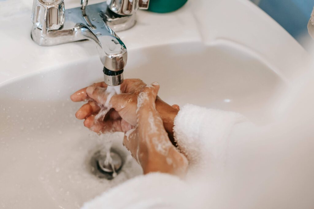 Mani che si lavano in un lavandino con acqua e sapone.