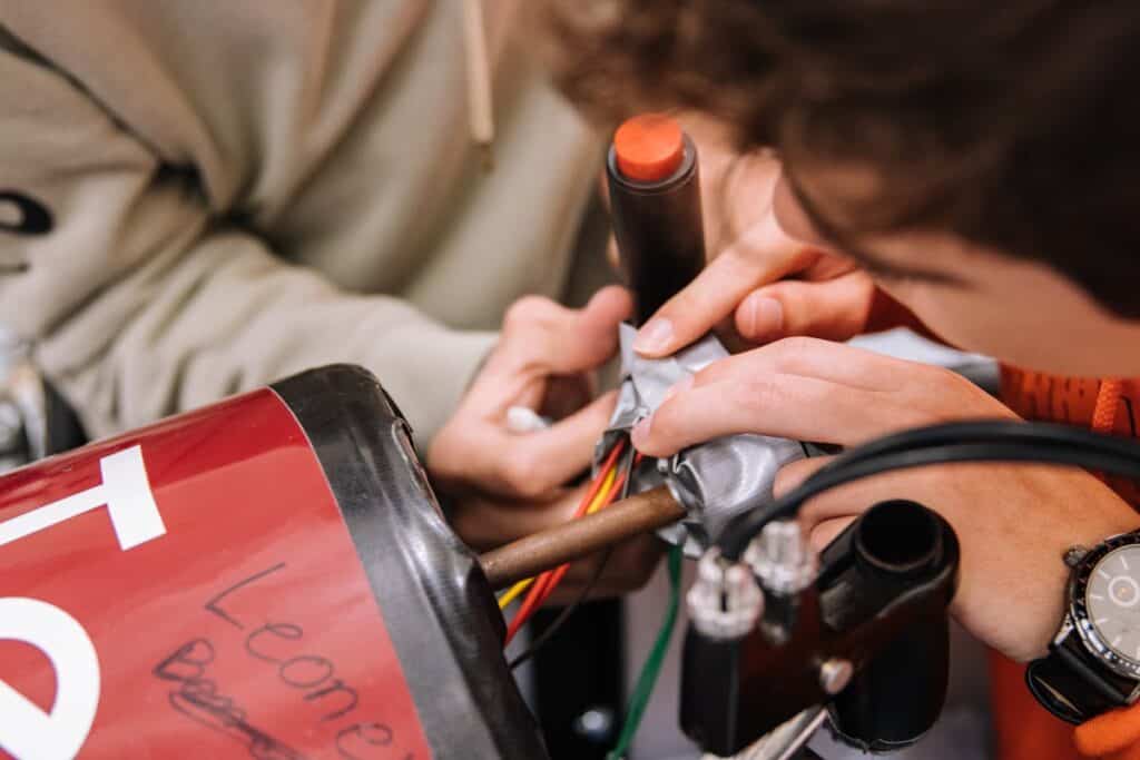 Due persone riparano un componente elettrico rosso.