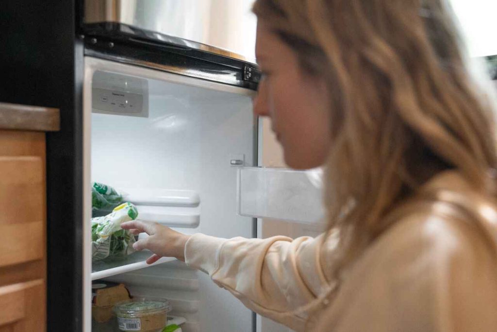 Come sbrinare il freezer: una donna di fronte al suo congelatore